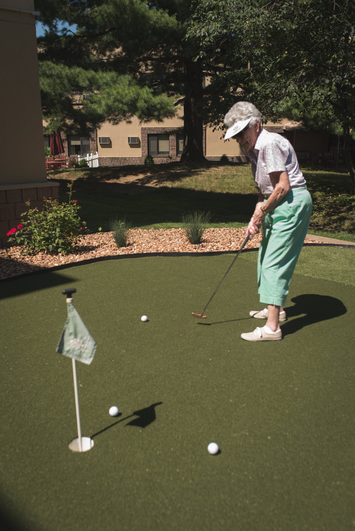 An elderly person enjoying a game of golf on an outdoor putting green.