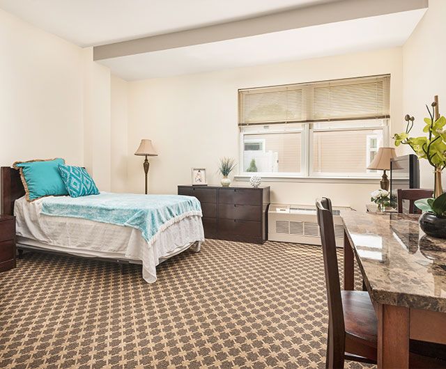 A cozy bedroom with a single bed, desk, and window providing natural light.