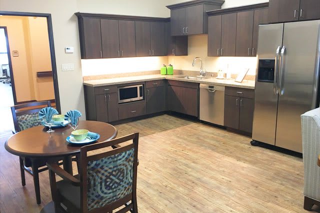 A modern kitchen with sleek cabinets, stainless steel appliances, and a small dining area.