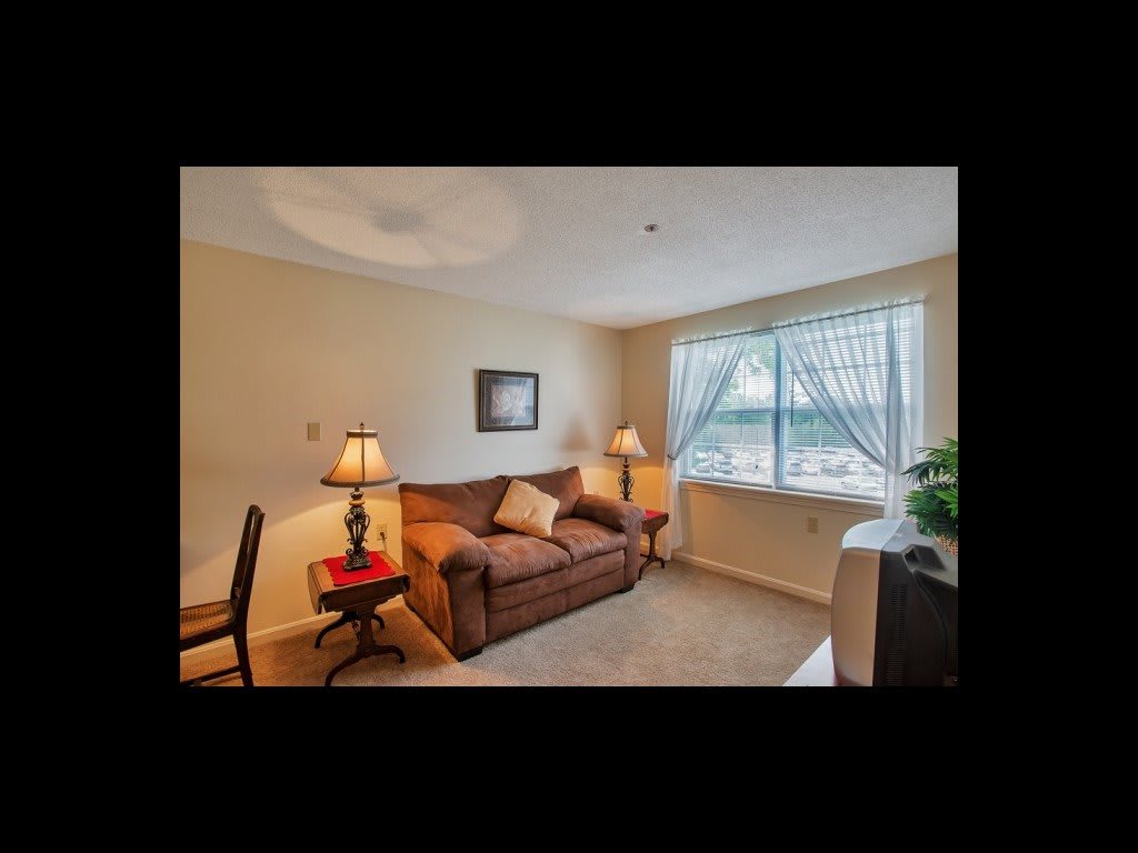 Cozy living room with a sofa, two lamps, and a window letting in natural light.