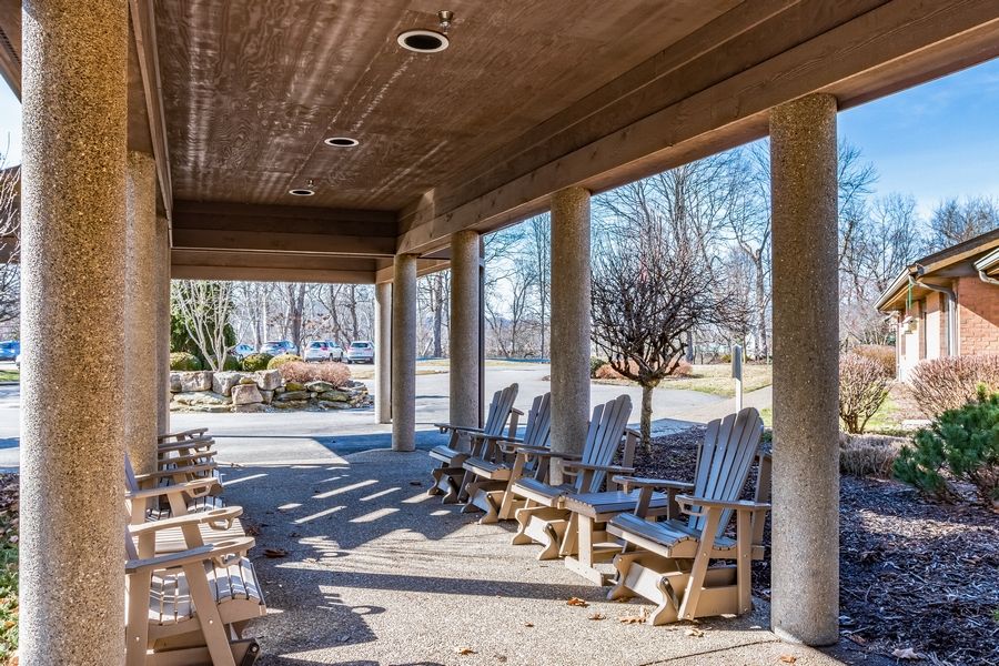 A porch with wooden chairs overlooking a sunny outdoor area.
