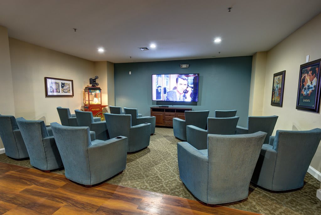 A cozy media room with comfortable seating arranged for viewing a large television screen.