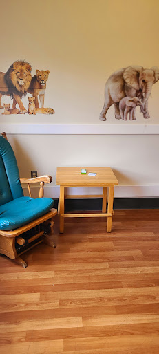 A cozy children's room featuring a rocking chair and a small wooden table.
