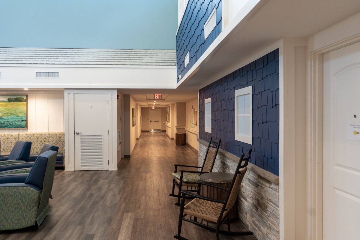 A modern hallway with rocking chairs, featuring blue walls and wood flooring.