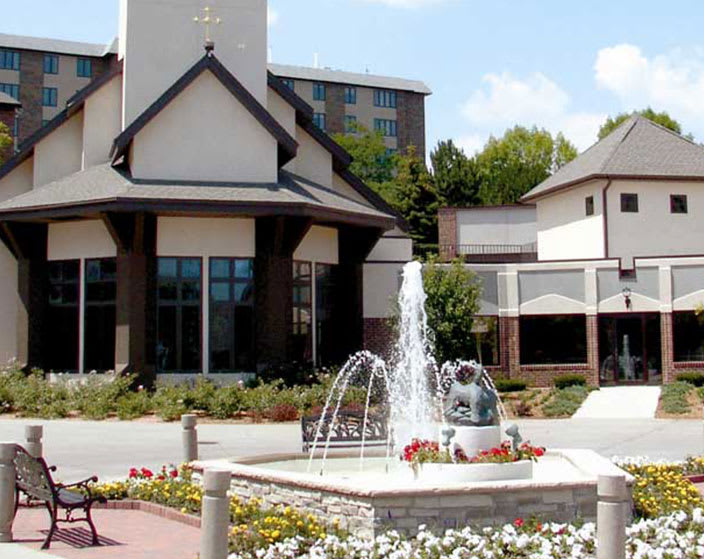 A scenic view of a fountain in front of a modern building with clear skies.