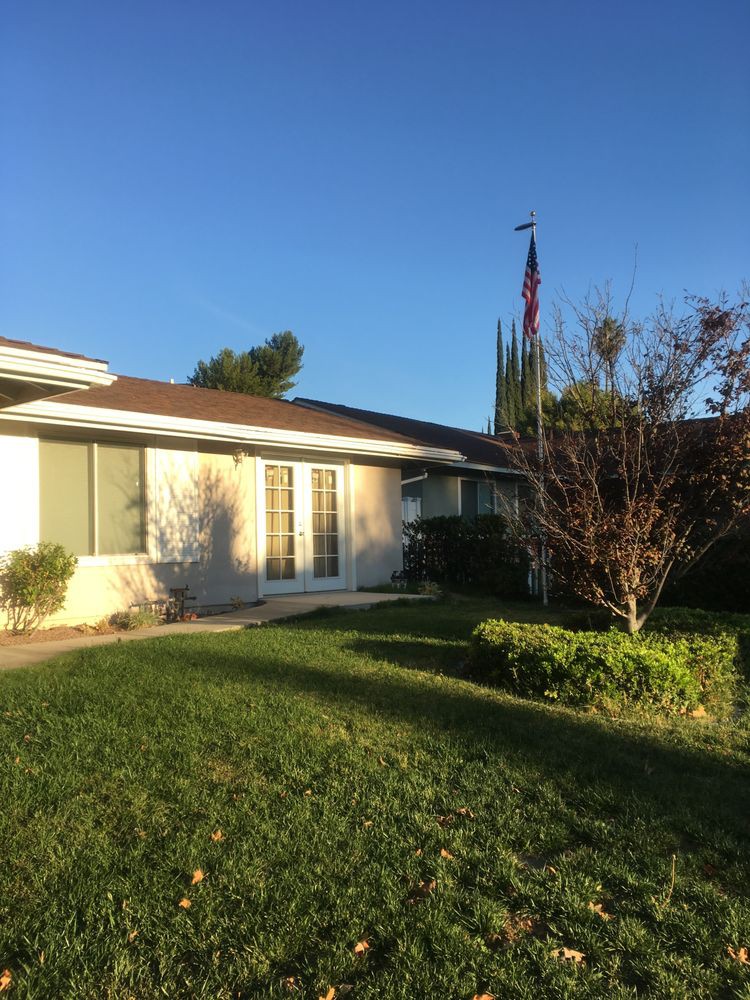 A suburban house with a well-maintained lawn and an American flag in the front yard on a sunny day.