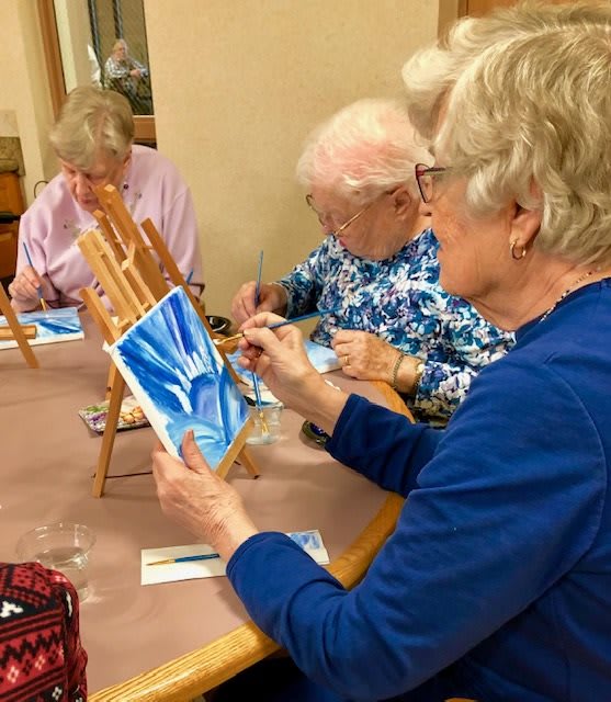 A group of seniors engaged in a painting class, each working on their own artistic creation.
