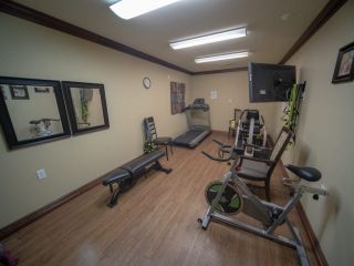 A small indoor gym equipped with a treadmill, weight machine, and benches.