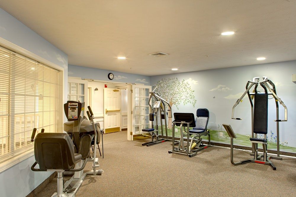 A gym with various exercise machines and equipment in a well-lit room.
