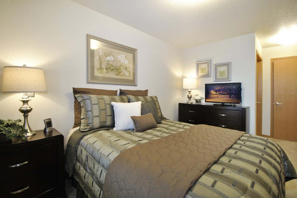A cozy and well-decorated bedroom with a bed, artwork, and a television.
