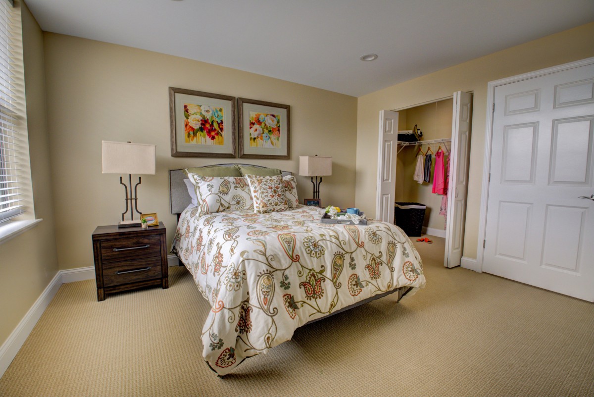 A cozy bedroom with floral bedding, modern lamps, and decorative artwork above the bed.