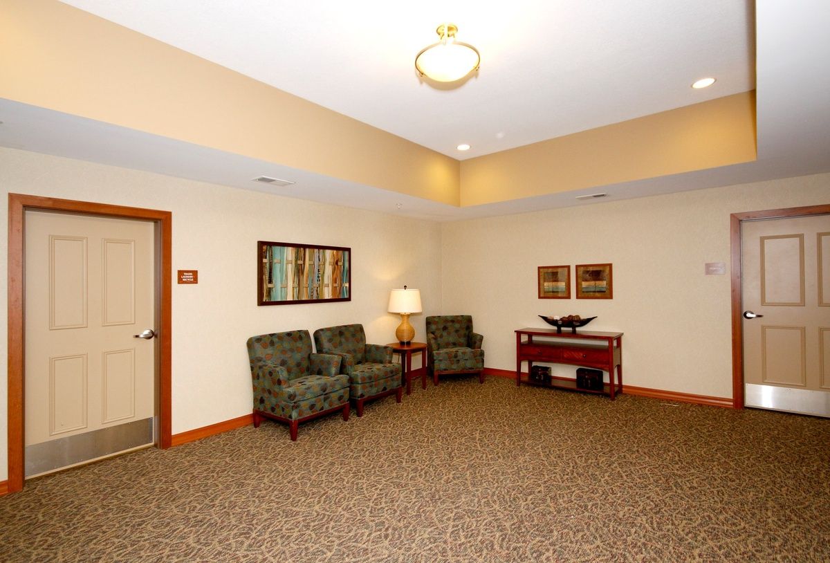 A neatly arranged waiting room with chairs, a lamp, and artwork on the walls.