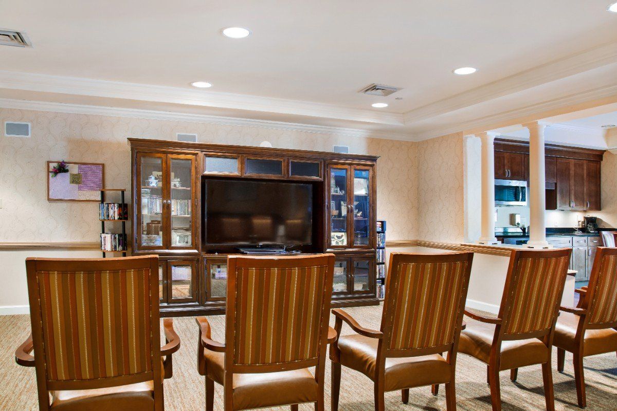 A cozy living room setup with wooden chairs facing an entertainment center and television.