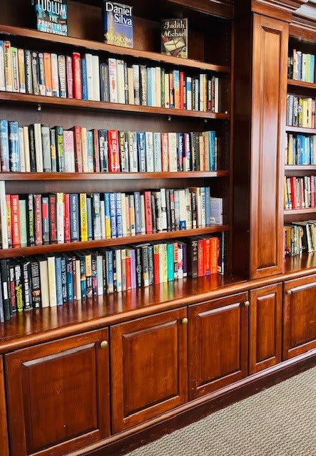 A well-organized wooden bookshelf filled with a variety of books in a library setting.