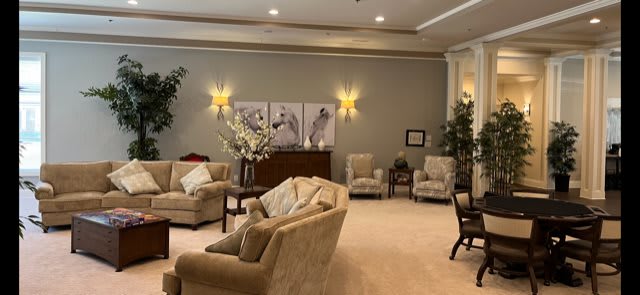 A cozy living room with comfortable sofas, armchairs, elegant lighting, and decorative artwork.