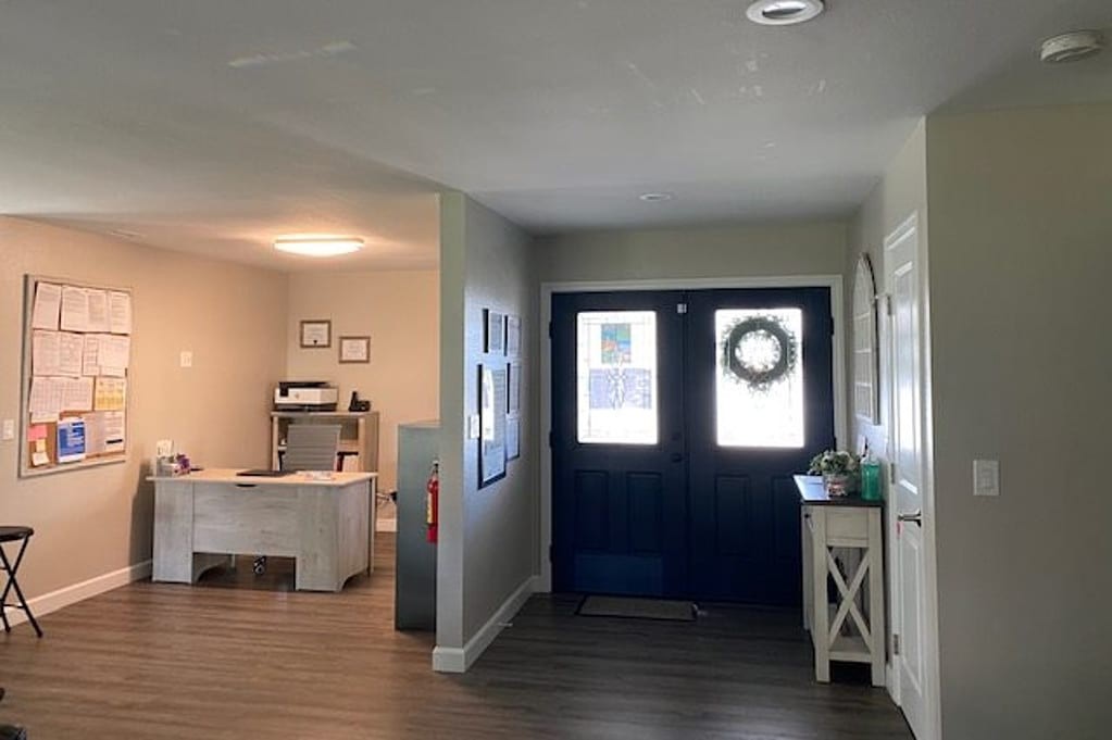 A cozy home entryway with a view into the living room, featuring a dark blue front door and rustic decor.