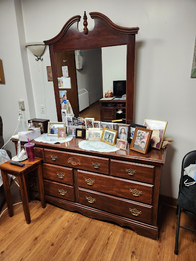 A classic wooden dresser with a mirror, adorned with various photo frames, situated in a cozy room.