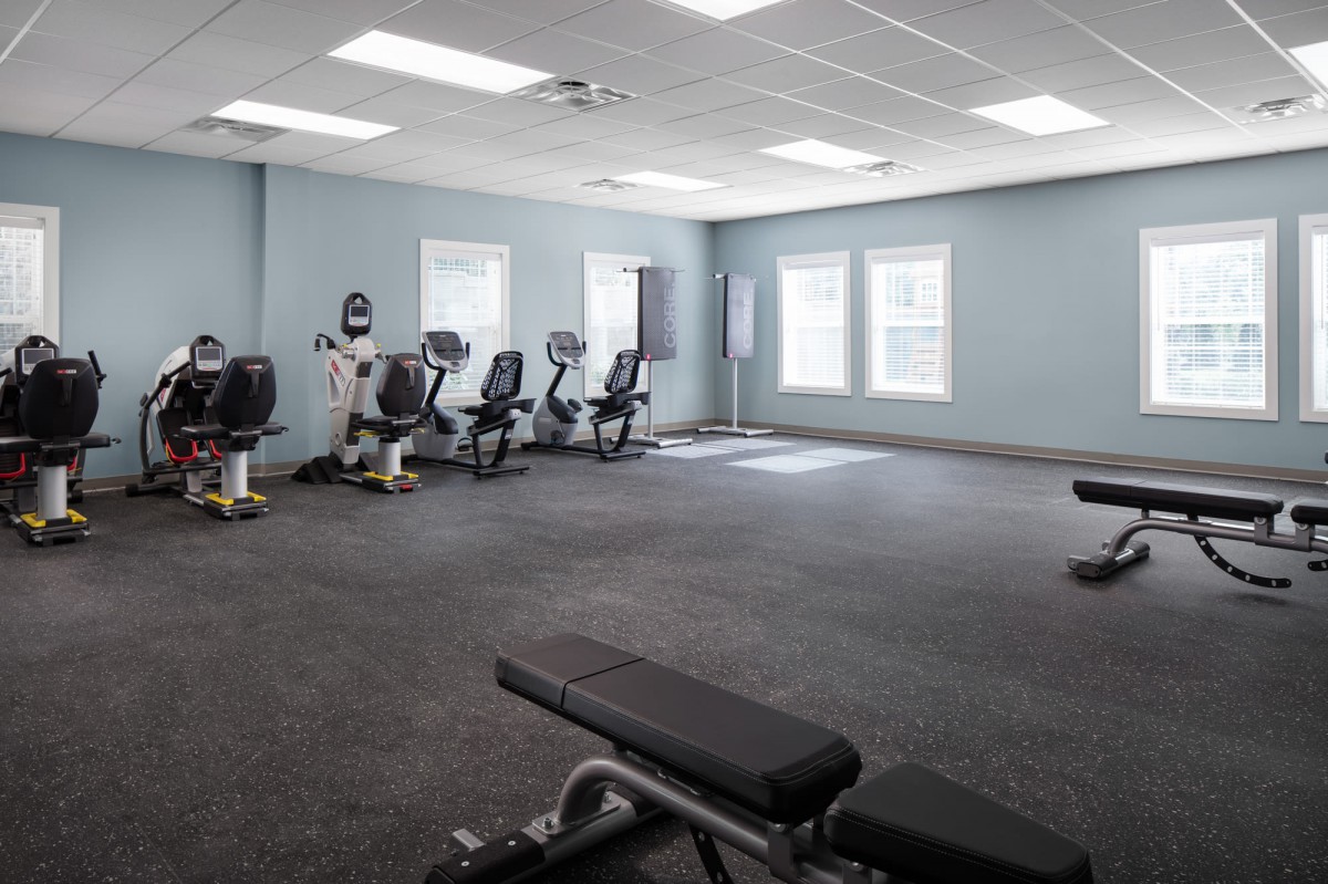 A well-lit gym with exercise bikes, benches, and open floor space for workouts.