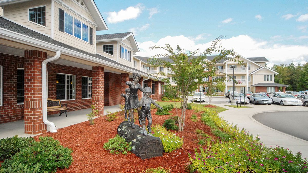 A landscaped garden with statues in front of a suburban building.