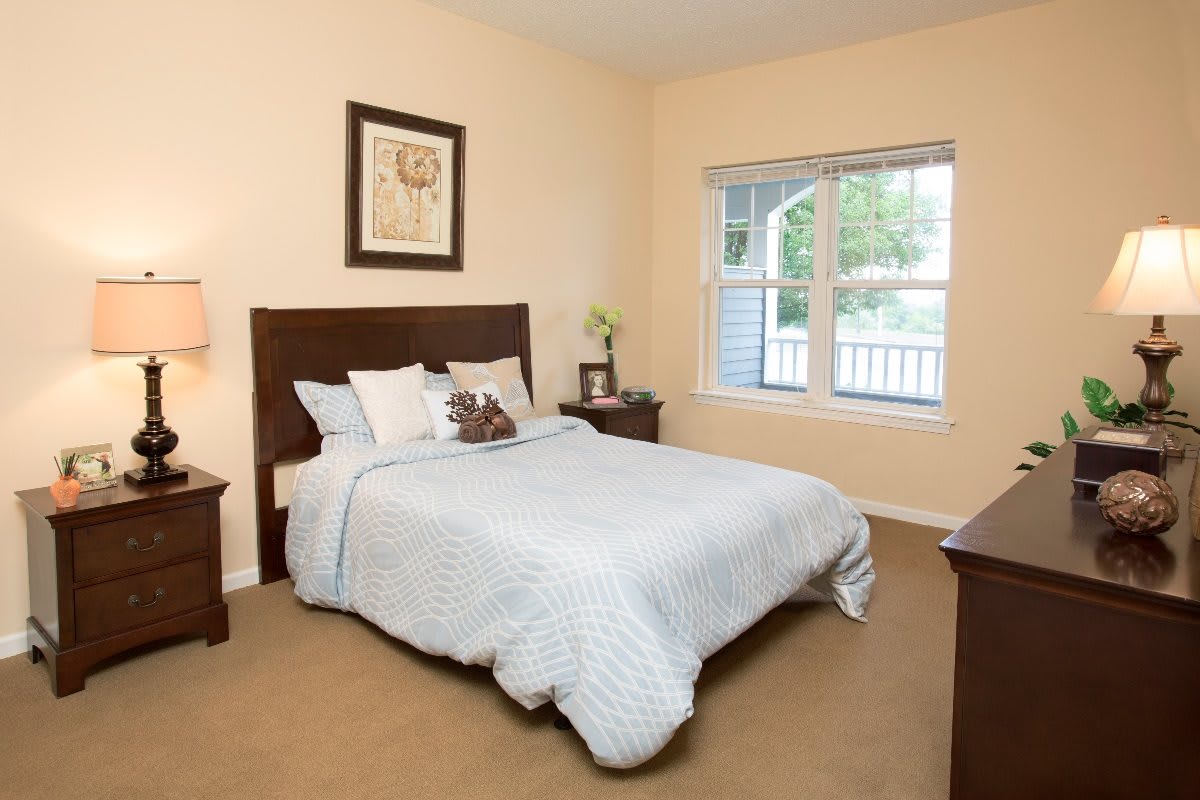 A cozy bedroom with a neatly made bed and natural light coming through the window.