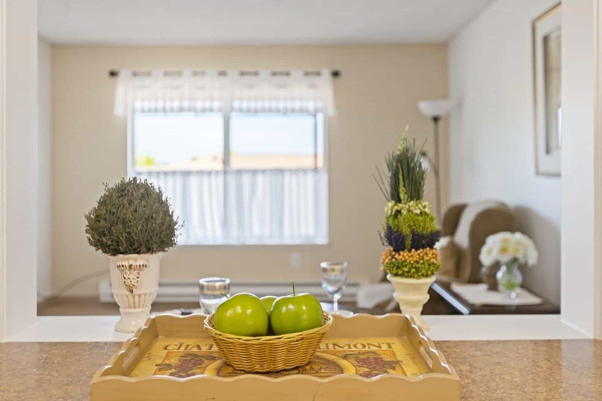 A cozy living room with a decorative tray featuring green apples and potted plants.