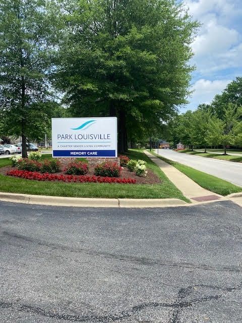 Entrance sign with landscaped surroundings and a driveway.