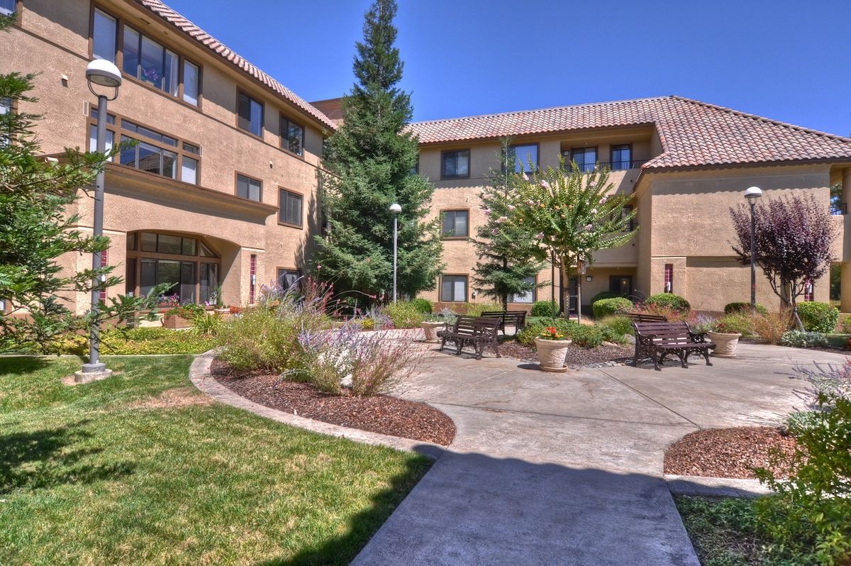 A well-maintained courtyard surrounded by a multi-story building, featuring benches and lush landscaping.