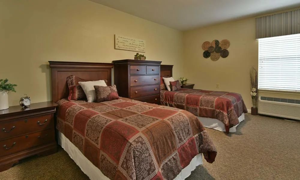 A cozy bedroom featuring two twin beds with patterned bedspreads and a wooden dresser.