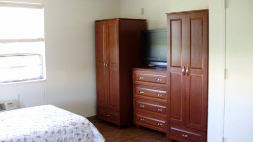 A cozy bedroom featuring wooden furniture, including a wardrobe and dresser, along with a TV.