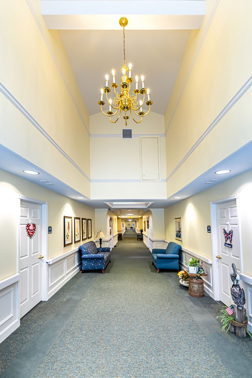 A well-lit hallway with a chandelier, featuring comfortable seating and decorative elements.