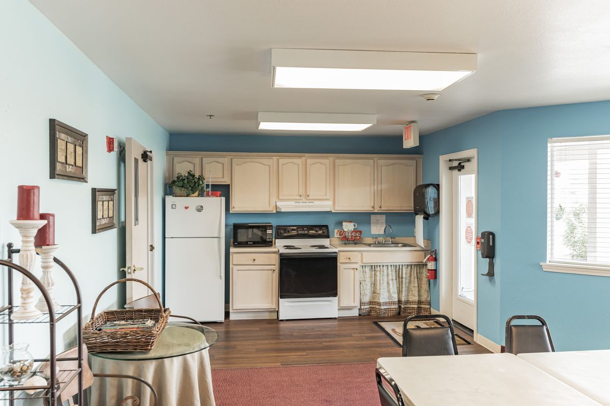 A cozy kitchen with light blue walls, beige cabinets, and essential appliances.
