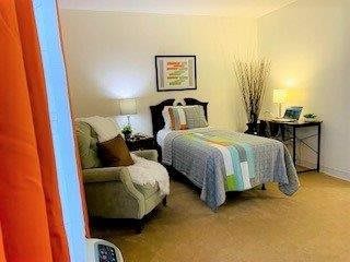 A cozy bedroom with a single bed, armchair, and soft lighting.