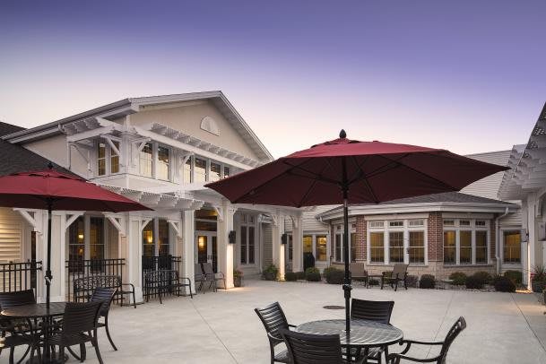 Outdoor patio area with tables, chairs, and umbrellas in front of a building.