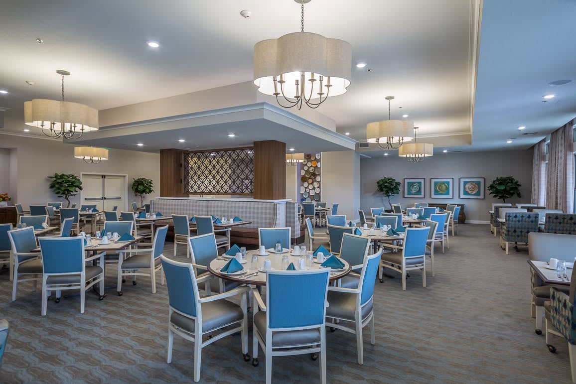 A modern dining area with blue-accented decor and elegant chandeliers.