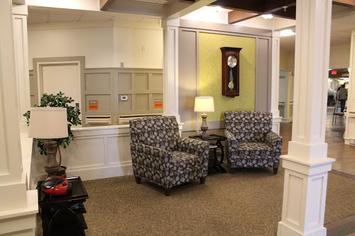 A cozy seating area featuring patterned chairs, a lamp, and a wall clock.