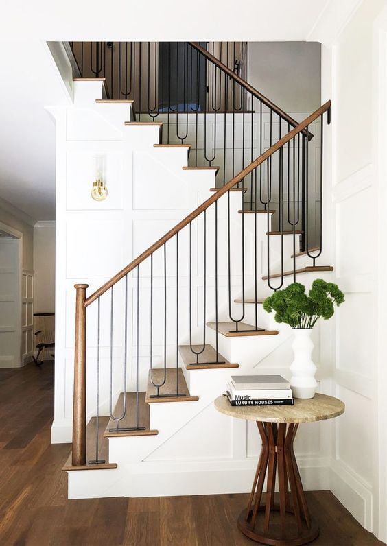 A stylish staircase with wooden steps and a metal railing, complemented by a minimalist table and plant decor.