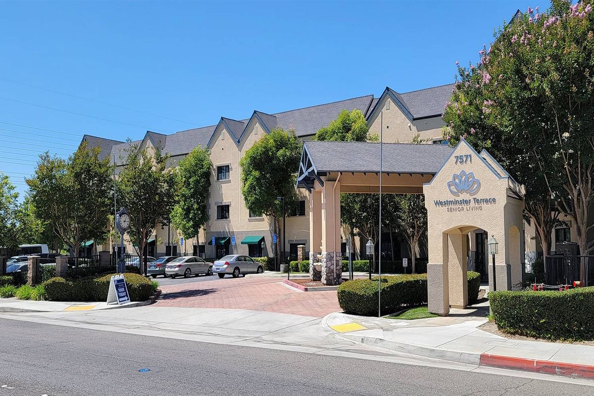 A view of a building with an arched entrance and parked cars on a clear day.