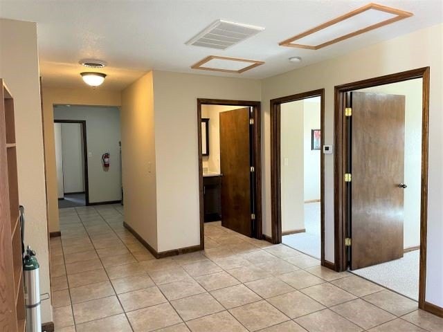 A simple hallway with tile flooring and multiple wooden doors.