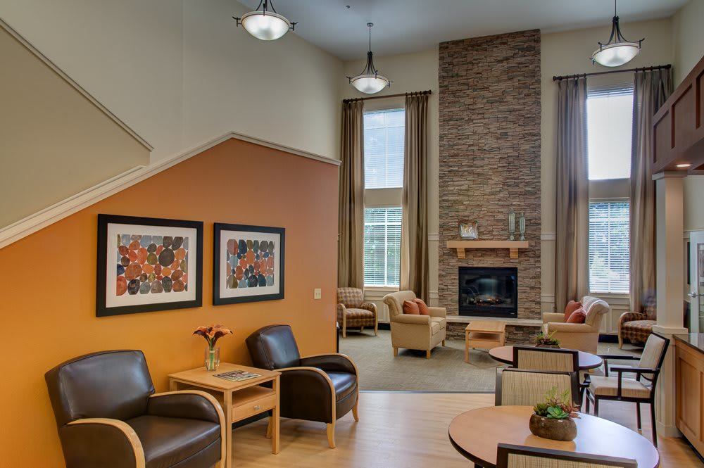 A modern living room with a cozy seating area, featuring a fireplace and decorative artwork on the walls.