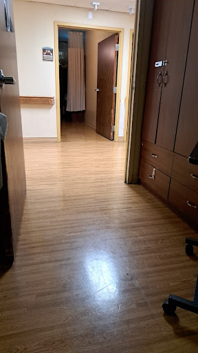 A view of a hallway with wooden flooring and open doors leading to different rooms.