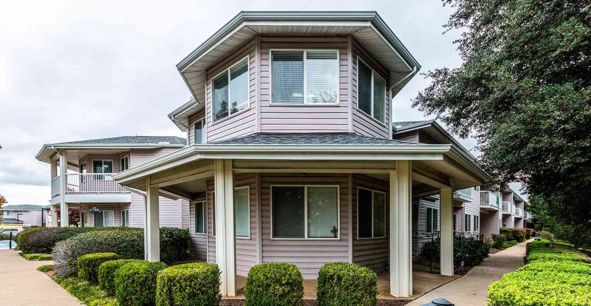 A two-story residential house with large windows and a covered porch.