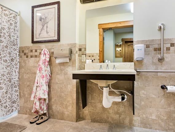 A well-appointed bathroom with a wall-mounted sink, decorative tiles, and a floral robe hanging by the side.