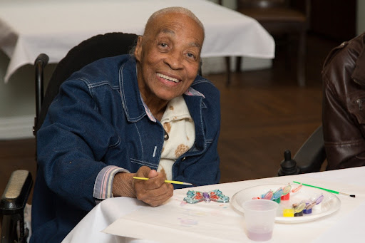 An elderly individual joyfully engaging in a painting activity.