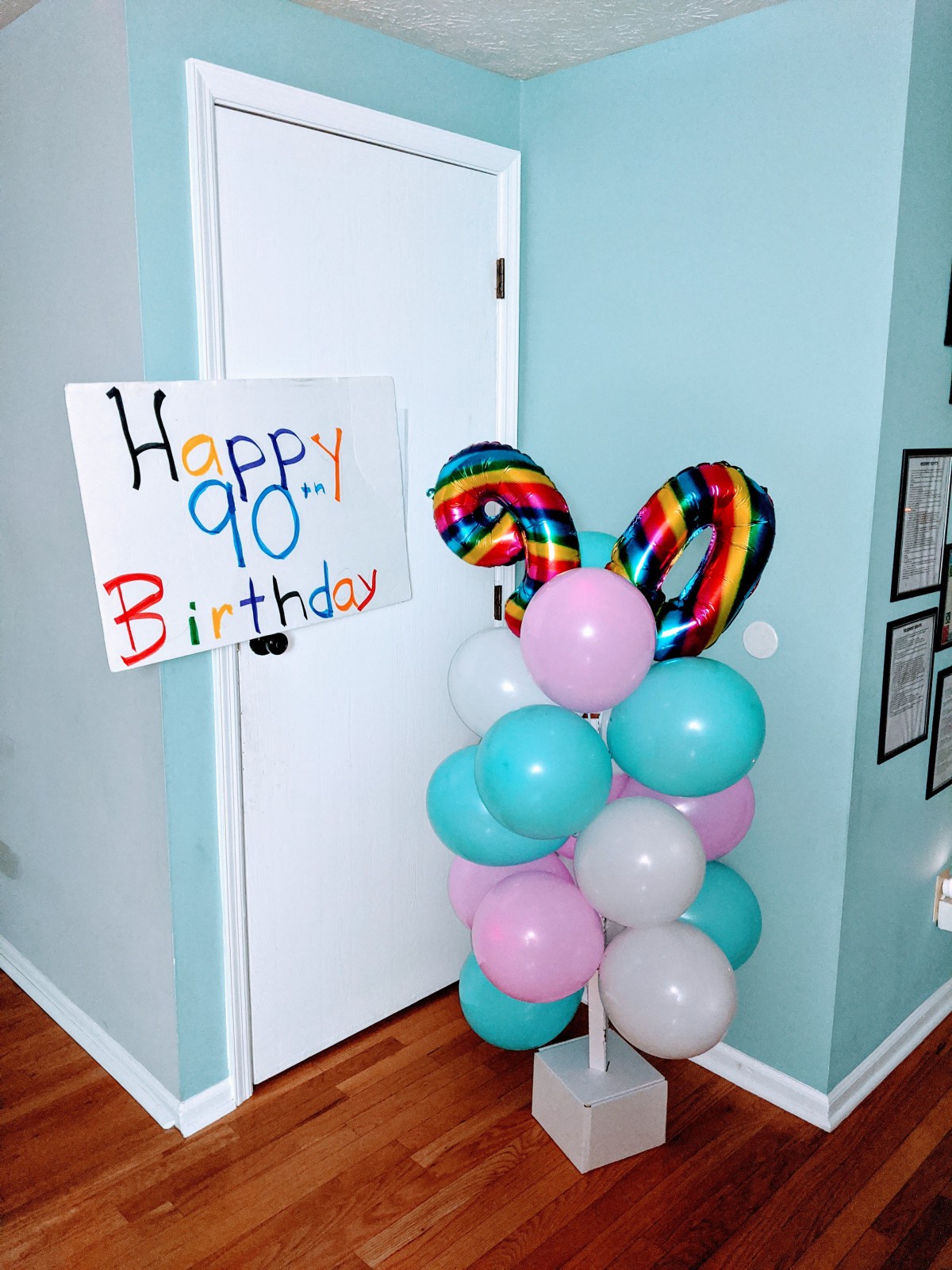 A colorful setup with balloons and a 'Happy 90th Birthday' sign in a room.