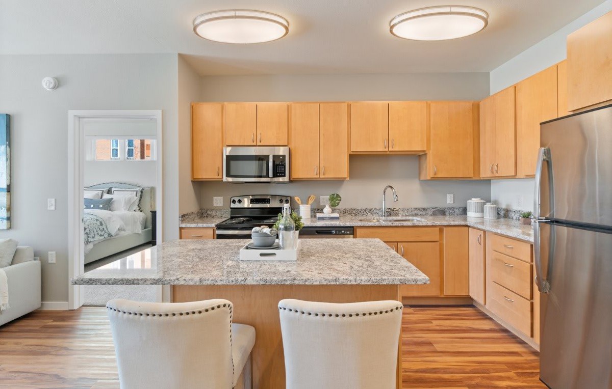 A modern kitchen with wooden cabinets, granite countertops, and stainless steel appliances.