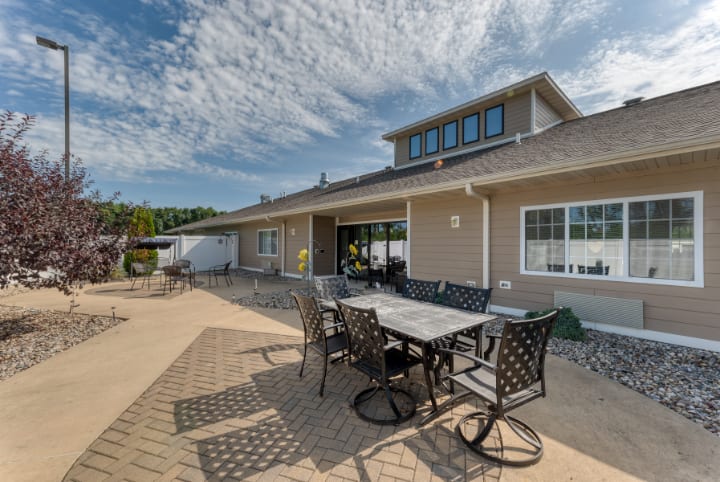 A spacious outdoor patio area with a dining table and chairs in a sunny backyard.