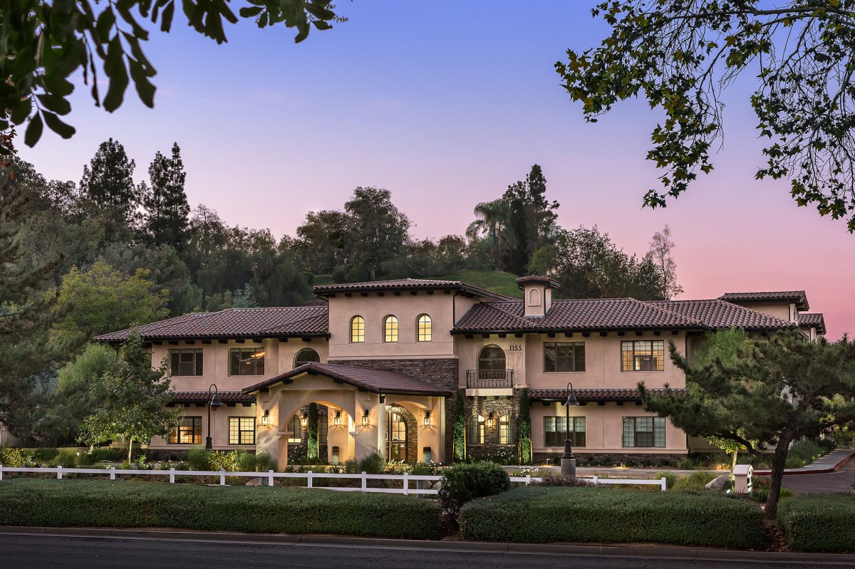 A luxurious mansion surrounded by trees during the evening.