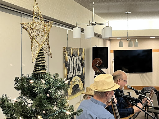 A festive indoor scene featuring a decorated Christmas tree and musicians performing, celebrating the holiday spirit.