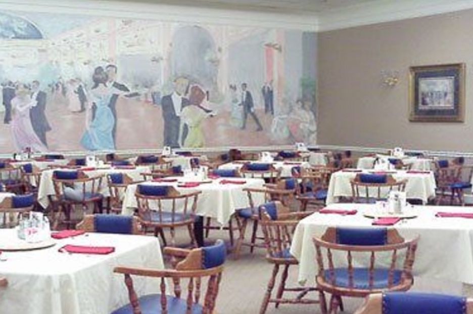 An elegant restaurant dining area with neatly arranged tables and chairs, featuring a large mural on the wall.