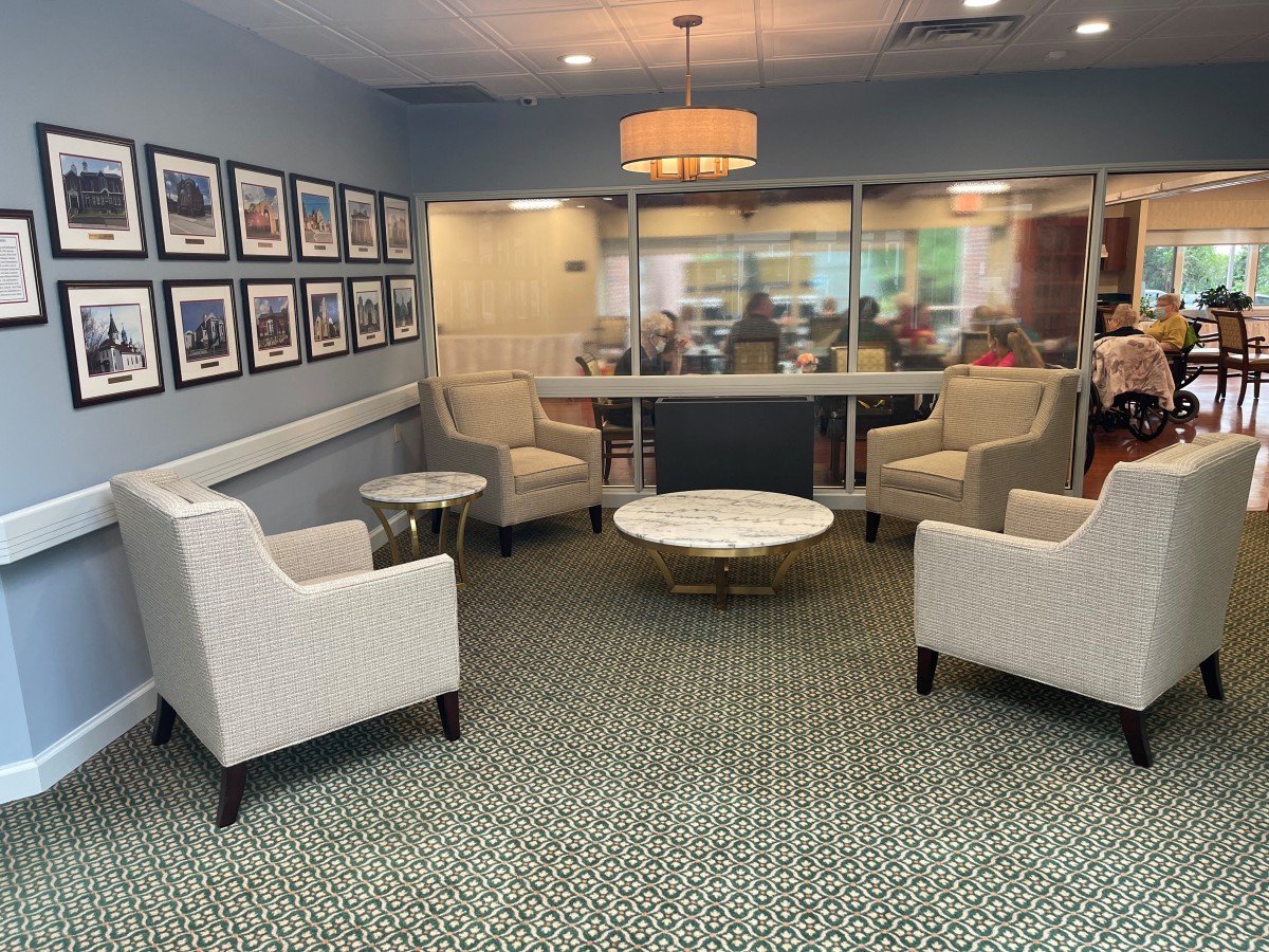 A cozy waiting room featuring armchairs and a round coffee table with framed pictures on the wall.